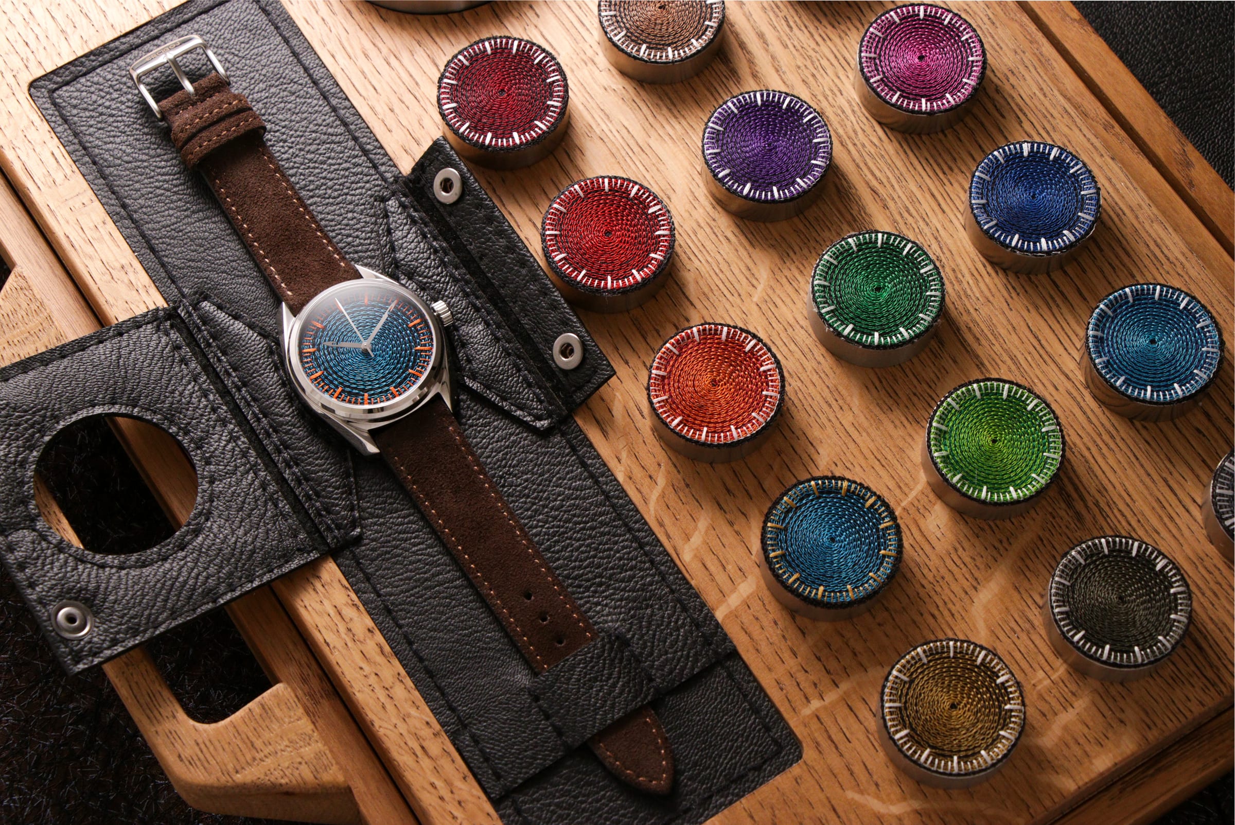 Chenille-embroidered watch dials in the studio's wooden tray, ready for casing